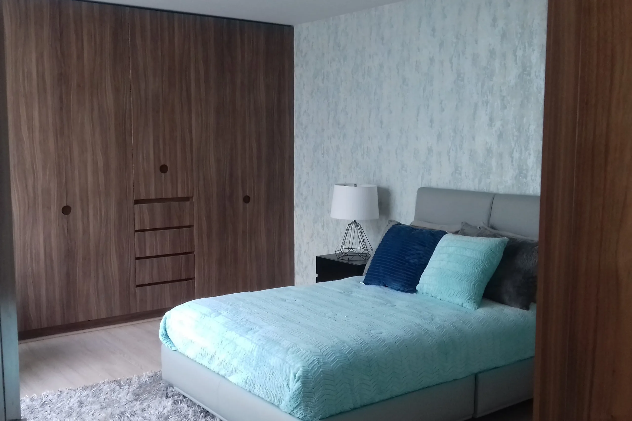 Closet de piso a techo en nogal con puertas abatibles y cajonería central