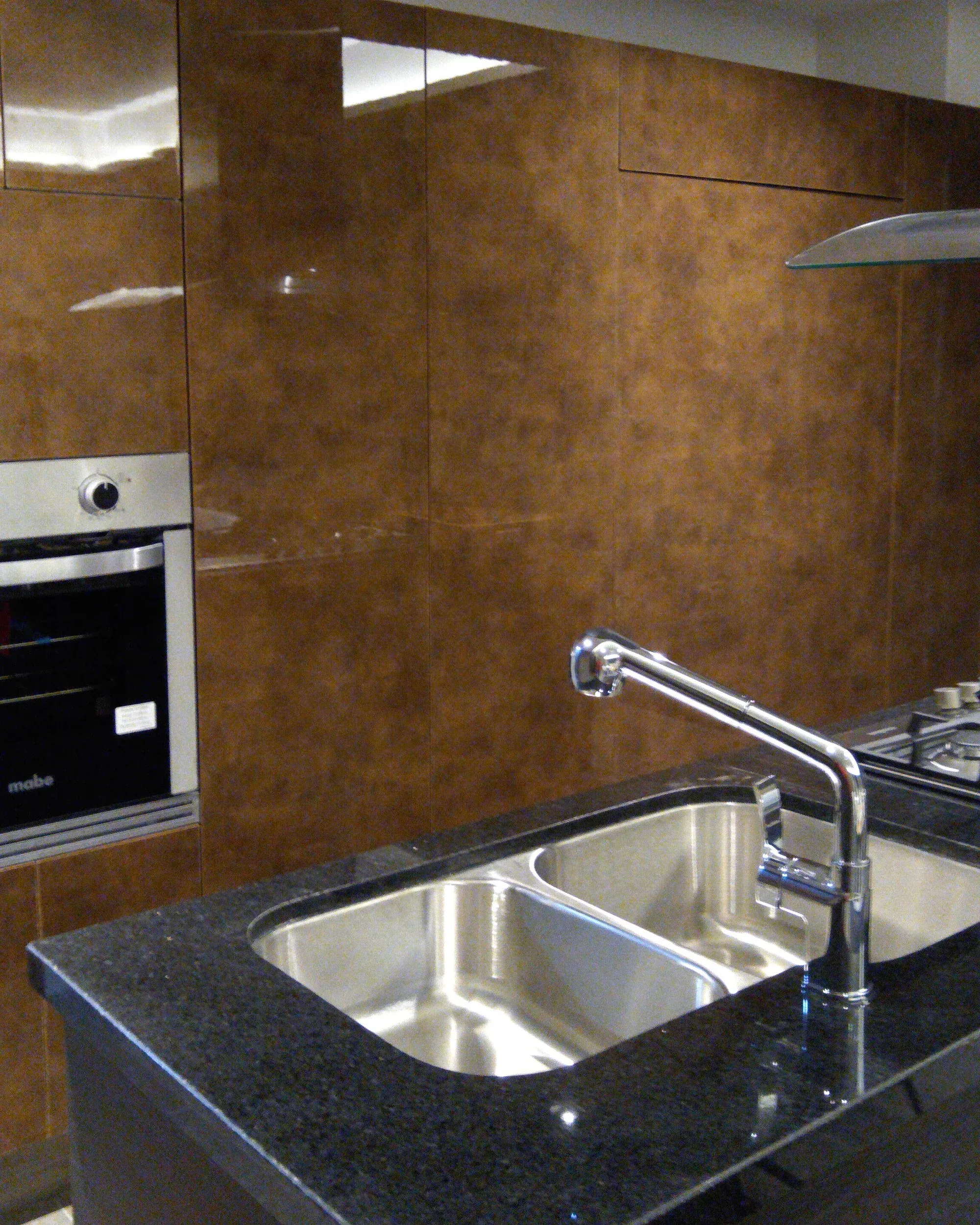 Cocina con frentes brillantes en tono cobre e isla con tarja doble