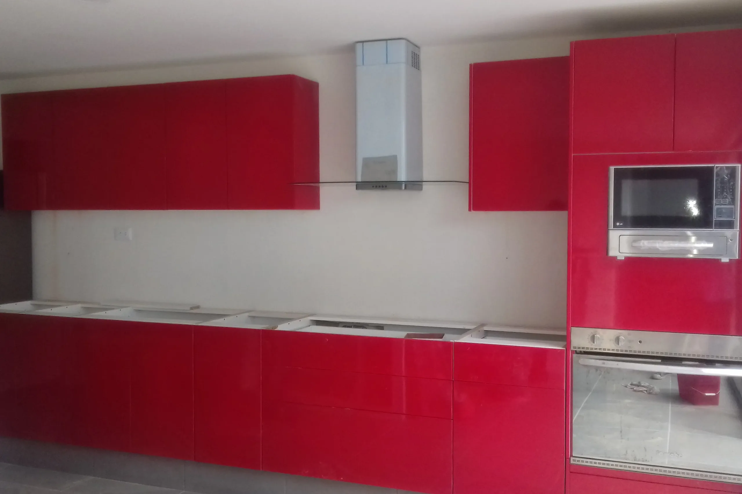Cocina integral con frentes lacados en rojo brillante y torre de horno y microondas