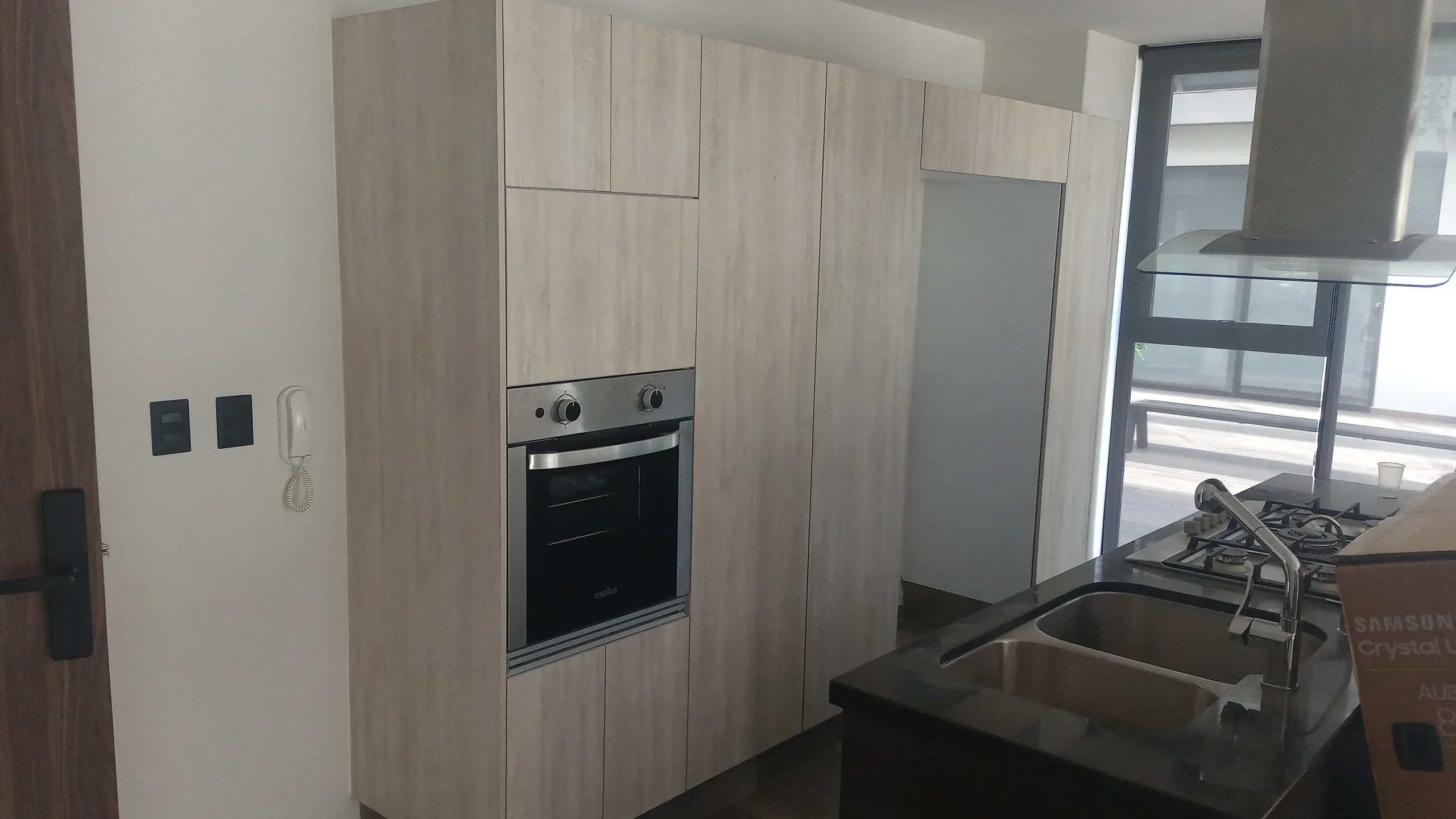 Cocina de departamento con frente continuo de madera clara de piso a techo e isla