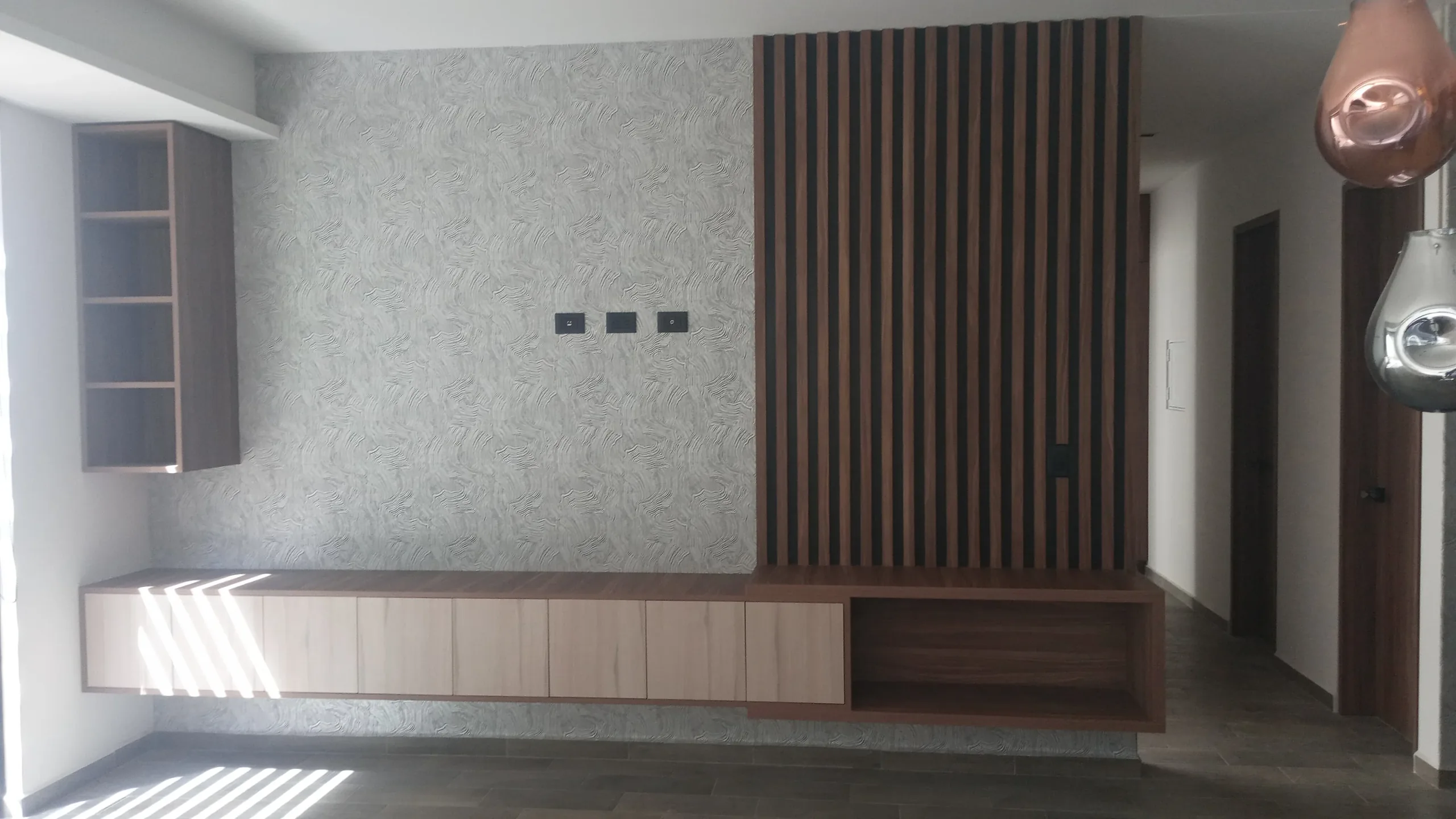 Mueble bajo colgado en la sala, con tablero de listones de madera hasta el plafón