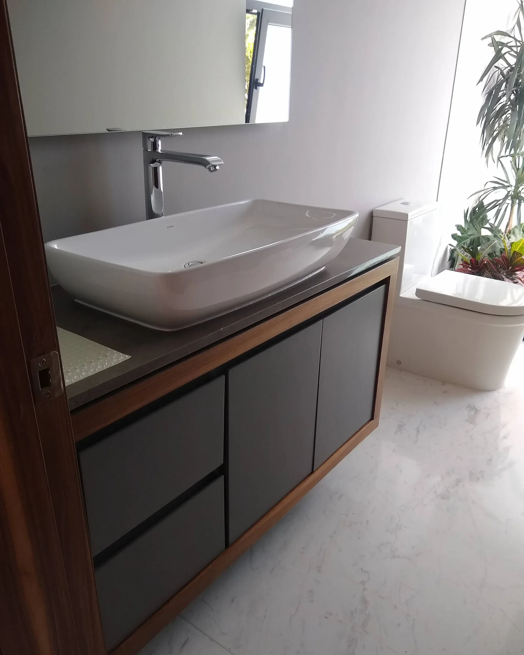 Mueble de lavabo colgado con marco de madera y cajonería lacada en gris