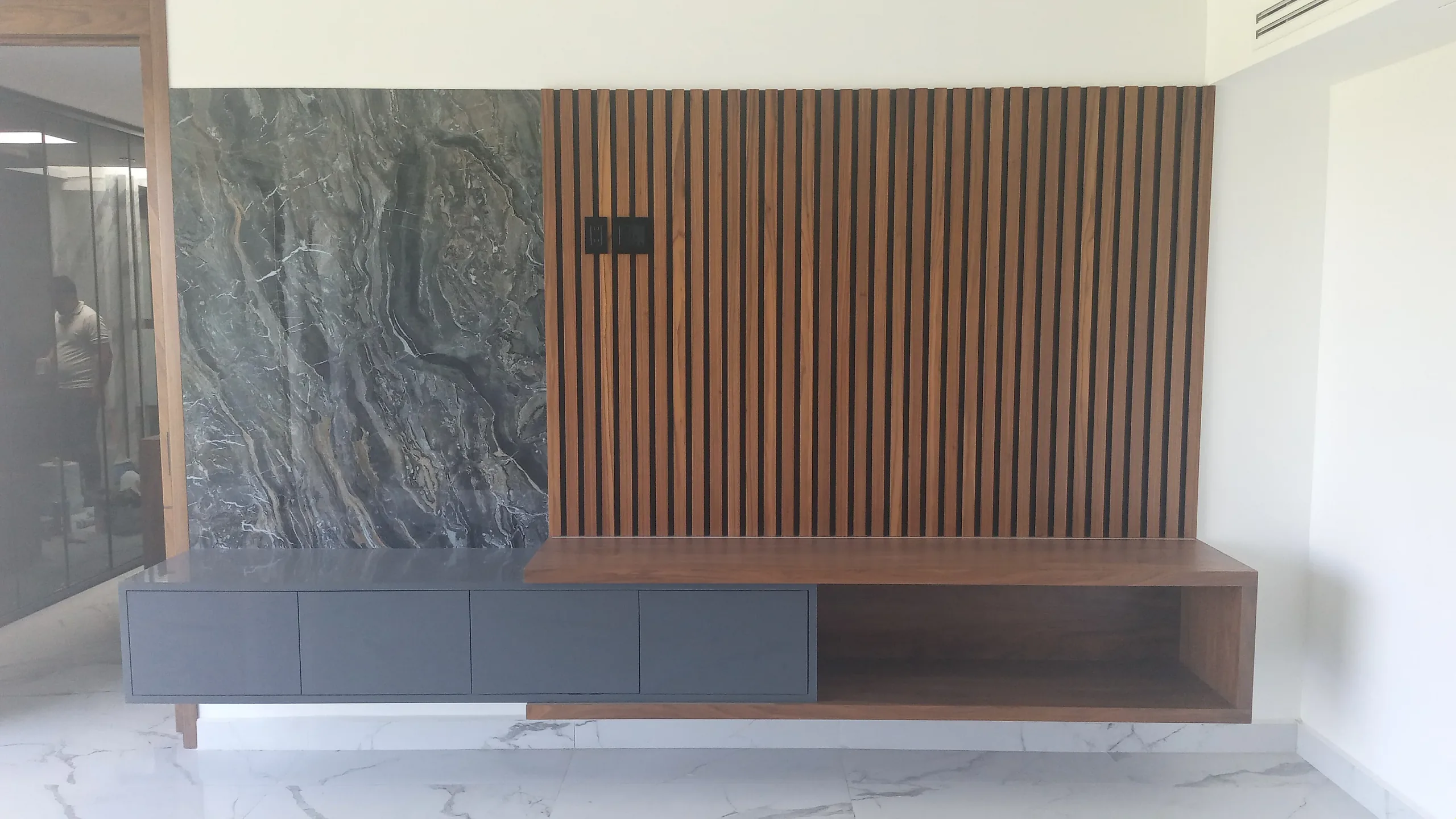 Muro de TV con lambrín de listones de madera, tablero de piedra y mueble bajo colgado