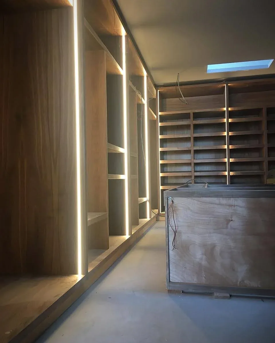 Vestidor de madera con módulos abiertos y tiras de luz en los montantes