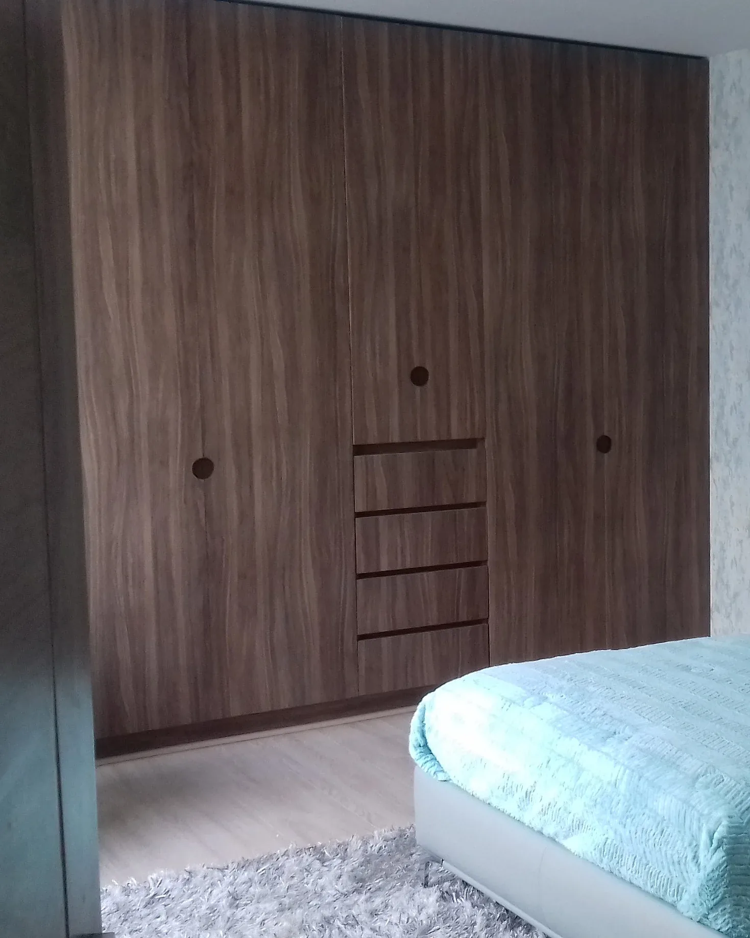 Closet de piso a techo en nogal con puertas abatibles y cajonería central