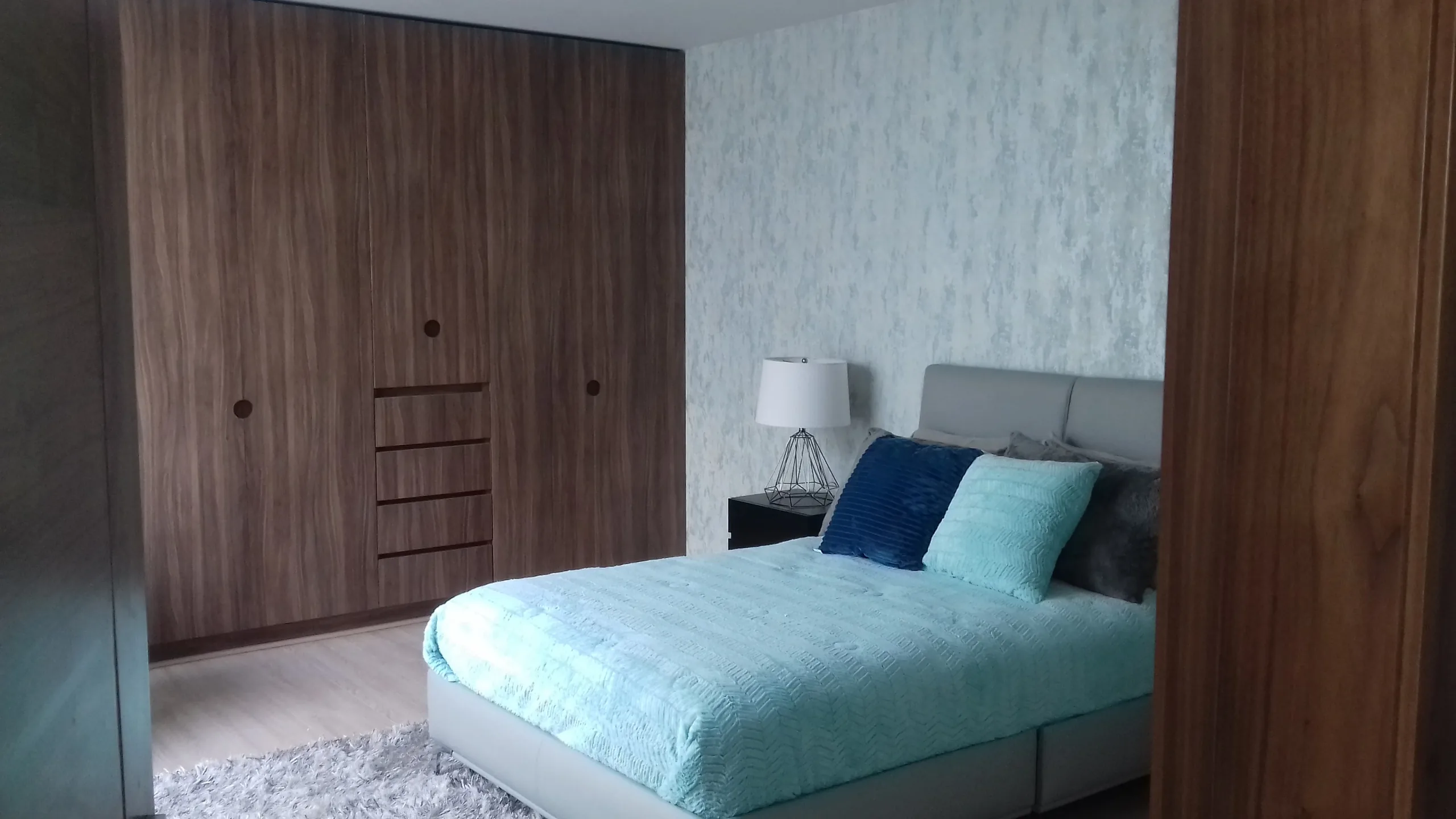 Closet de piso a techo en nogal con puertas abatibles y cajonería central