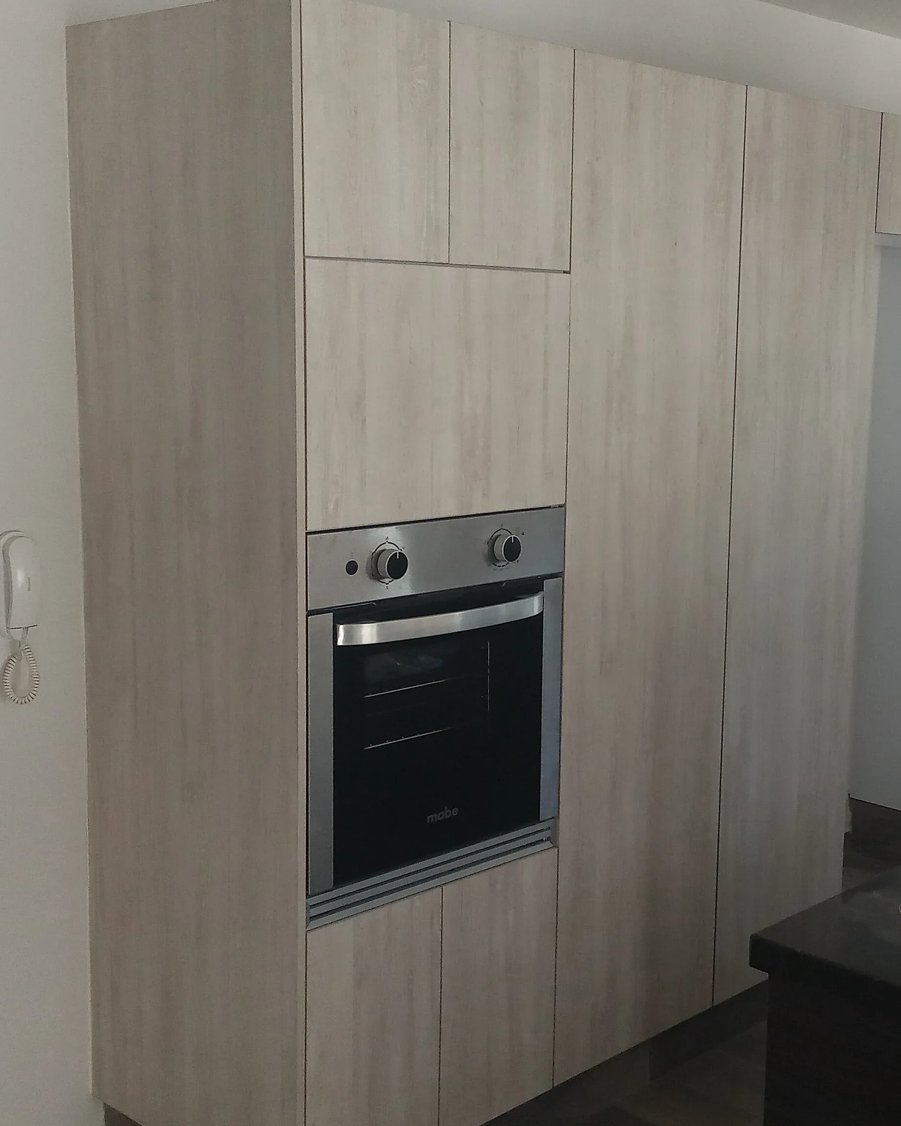 Torre de gabinetes de cocina en madera clara con horno empotrado